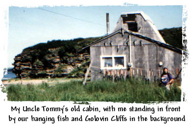 My Uncle Tommy's old cabin, with me standing in front by our hanging fish and Golovin Cliffs in the background.