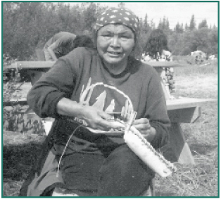 Lena Charley sewing a basket of birch bark and spruce roots.